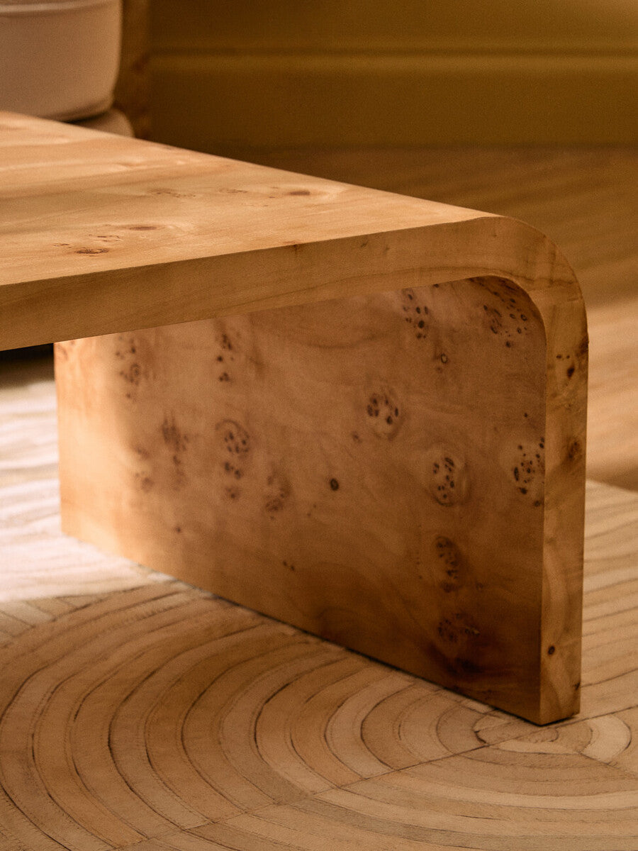 Natural burl wood curved coffee table with smooth edges by Orsina, showcasing a sleek, organic design and polished surface.