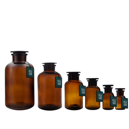 Group of amber glass apothecary jars used as bathroom decor, featuring vintage-style containers for storage and decoration.