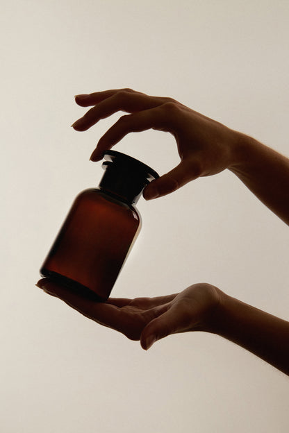 Amber glass apothecary jar from Kuishi, used as bathroom decor, featuring a vintage-style container with a lid.