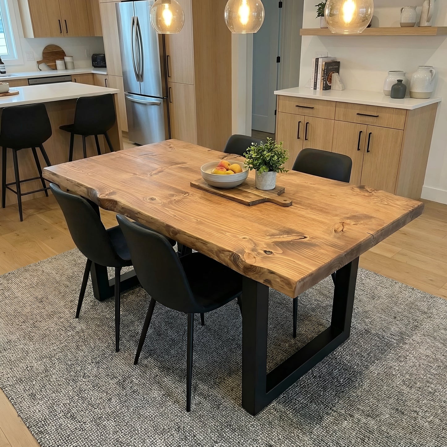 Waney edge wooden dining table with metal U-shaped legs by Tribe Joinery, showcasing natural wood grain and modern metal design.