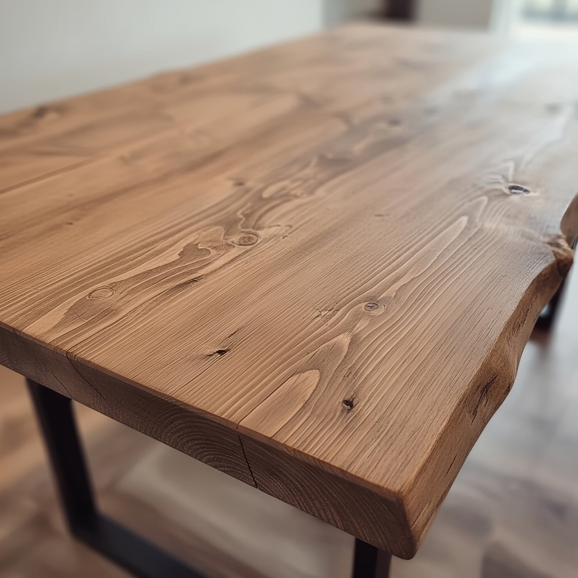 Waney edge wooden dining table with metal U-shaped legs, designed for a modern, rustic dining room setting.