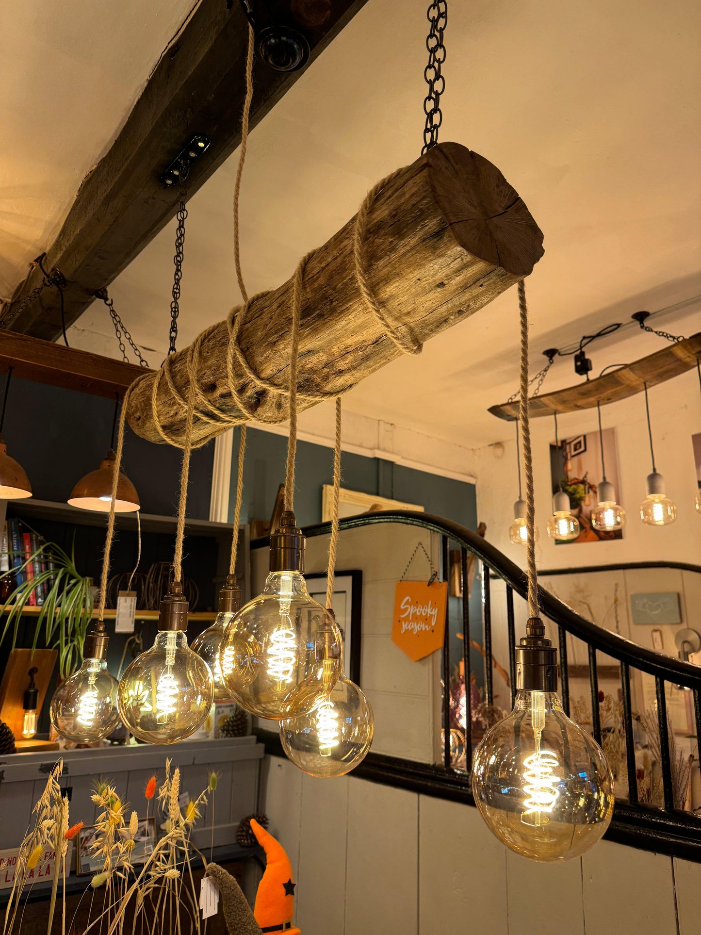 Rustic oak wrap-around chandelier by MooBoo Home featuring warm wood tones and elegant design, hanging from a ceiling with light bulbs.