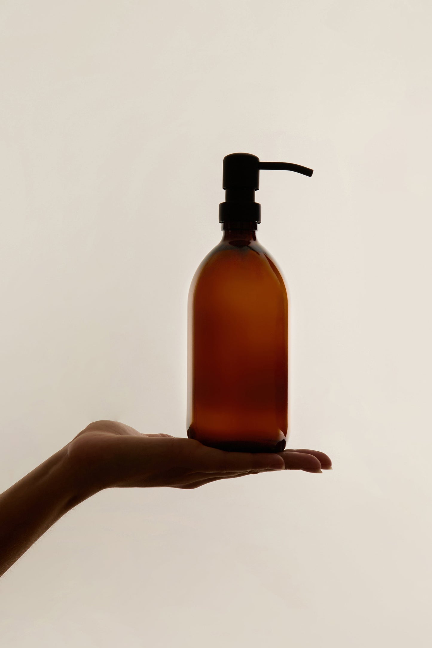 Amber glass soap dispenser with stainless steel pump by Kuishi, featuring a sleek, modern design for household use.