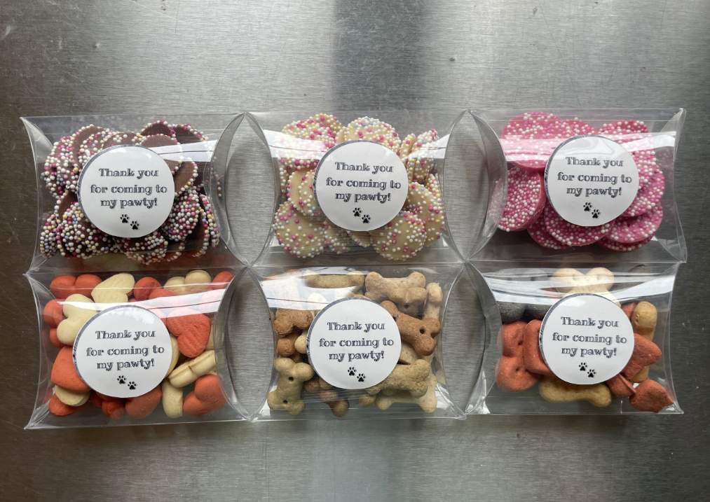Assorted dog biscuit treats in a pick and mix thank you box from The Bonnie Hound, featuring colorful pawprint packaging.