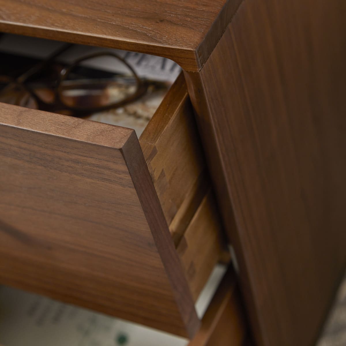 Fishe and Lilly Wright narrow walnut bedside table with a sleek design and a single drawer, placed in a modern bedroom setting.