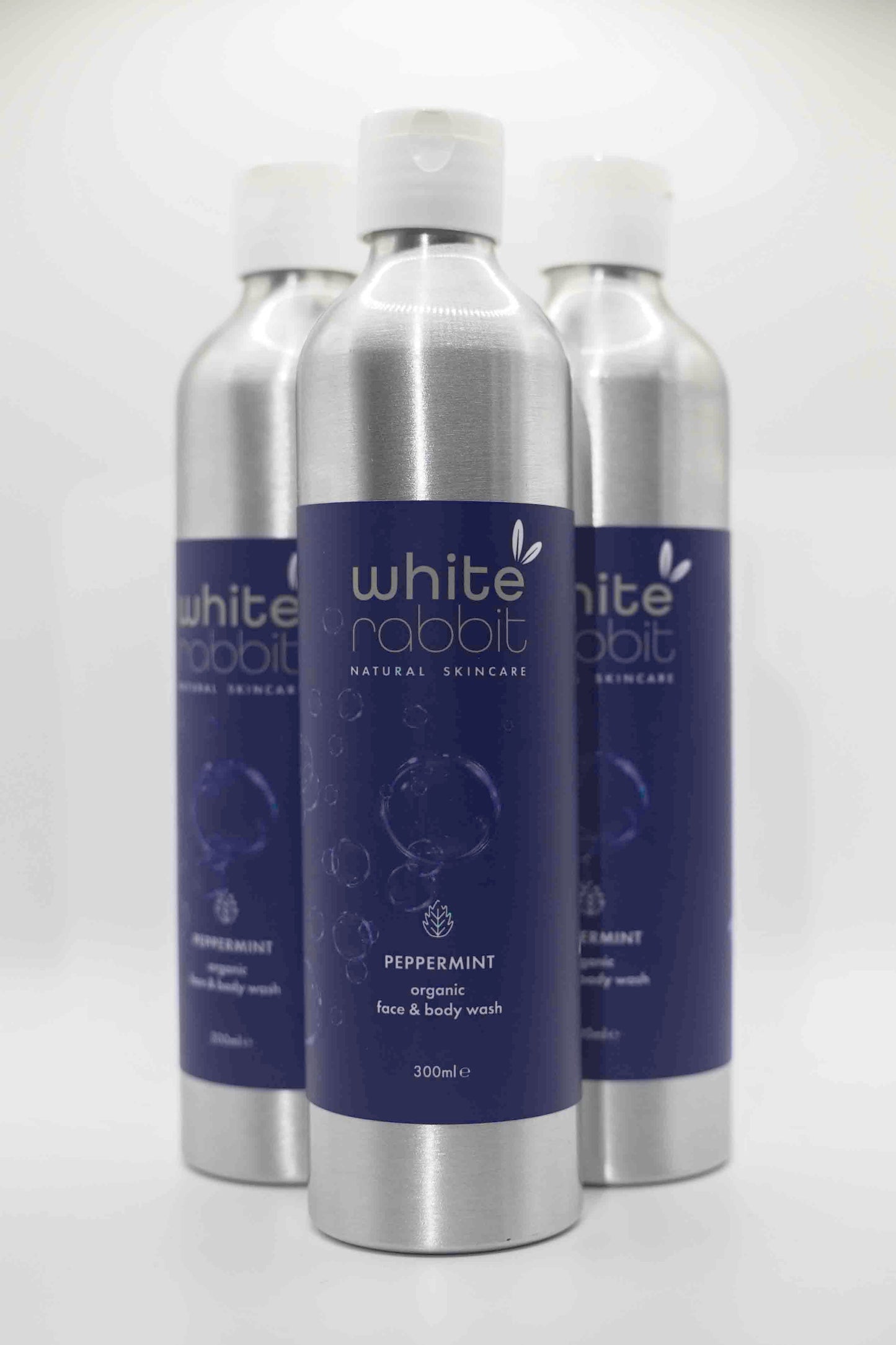 White Rabbit Organic Peppermint Face and Body Wash in a clear pump bottle, showing fresh mint leaves on the label.